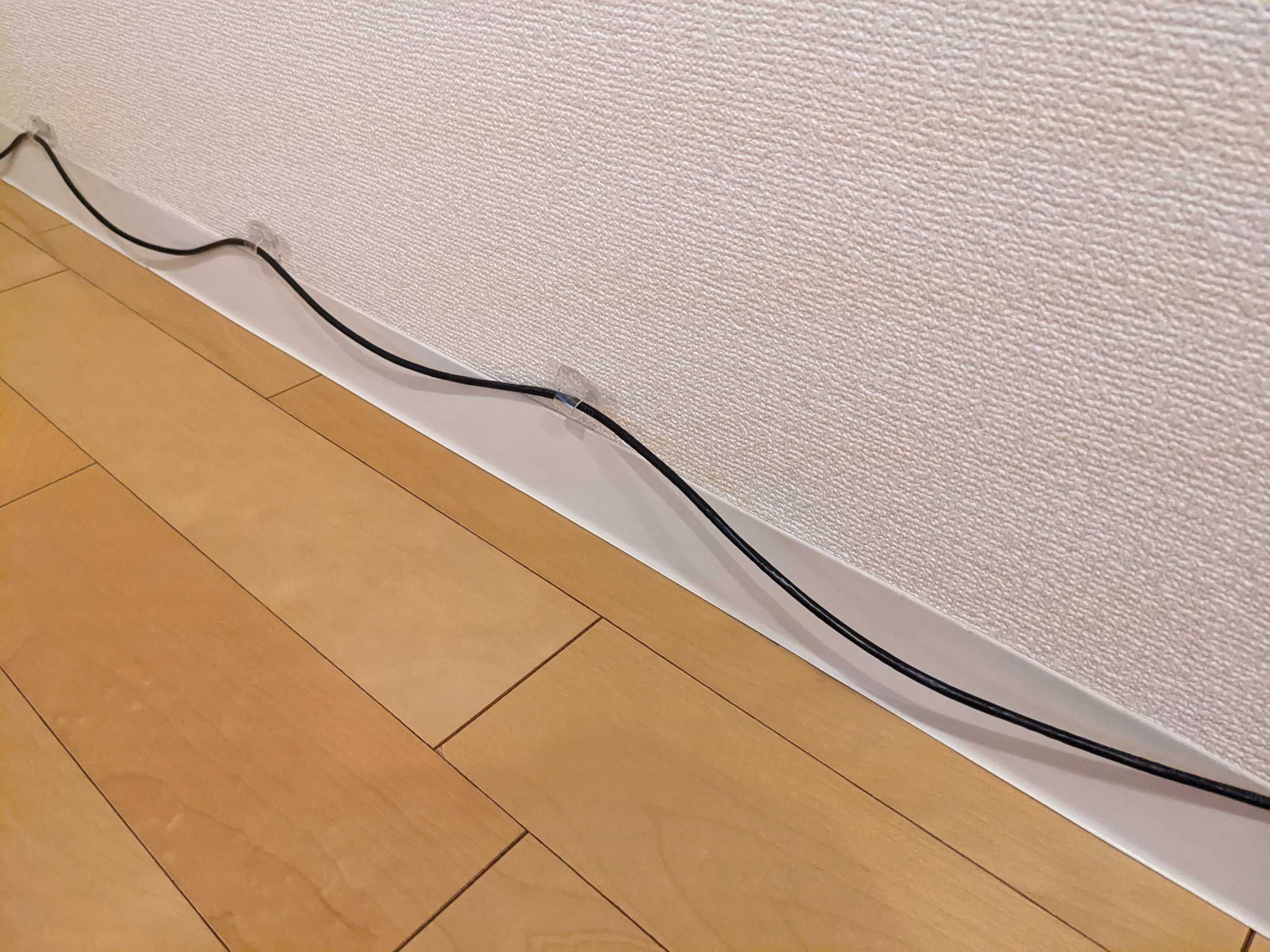 お掃除ロボットのためにLANケーブルを床から浮かせて配線した様子